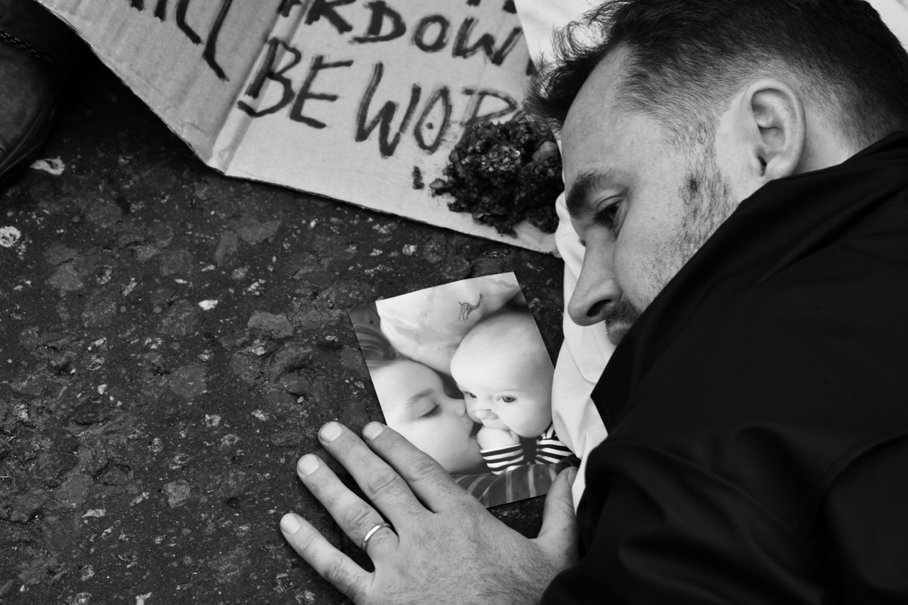 Protest man on floor next to photo of babies