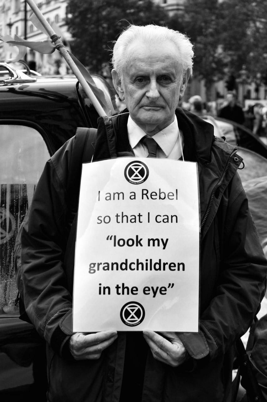 Protest grandad holding XR sign around neck.