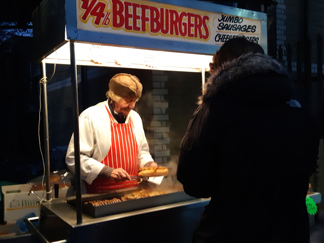 Image of man selling beefburgers from stall.