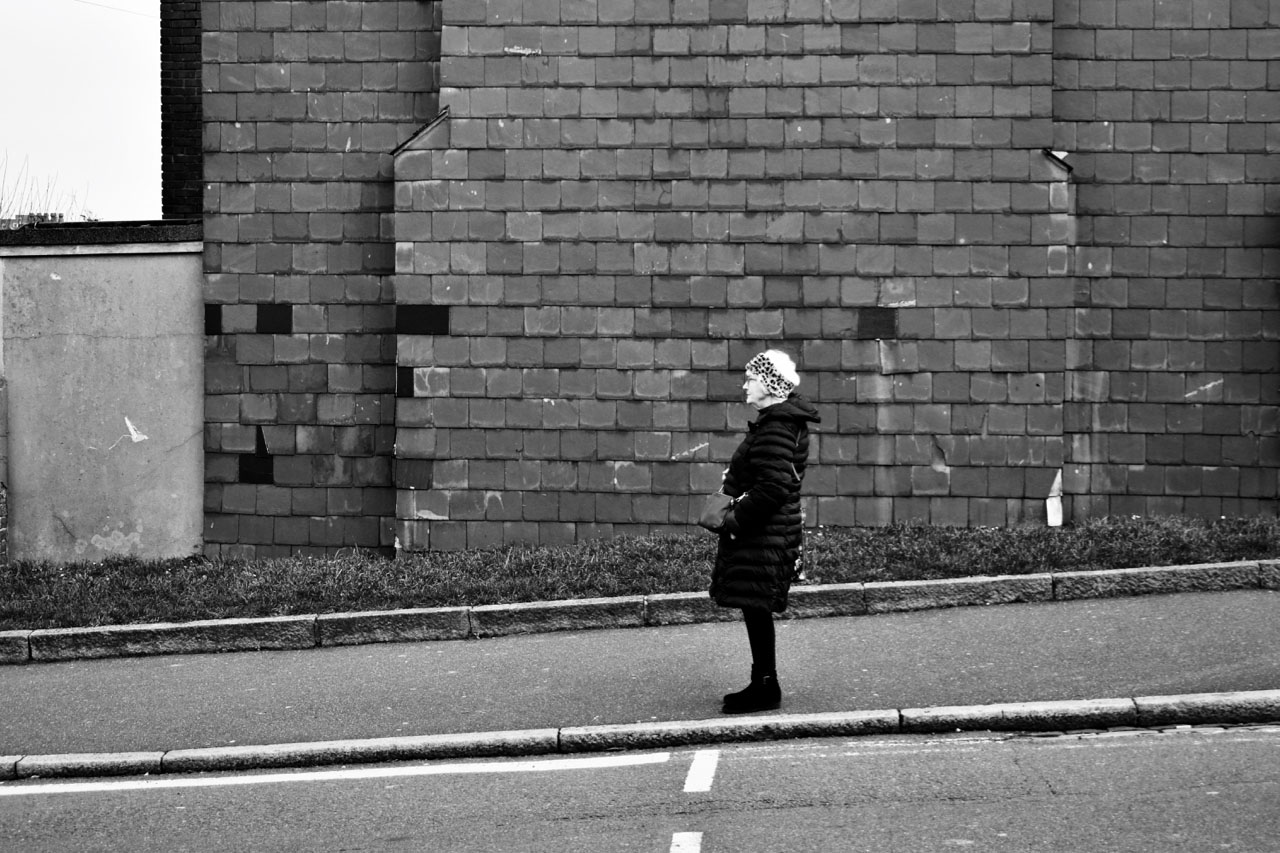 Image of solitary woman walking down angled pavement.