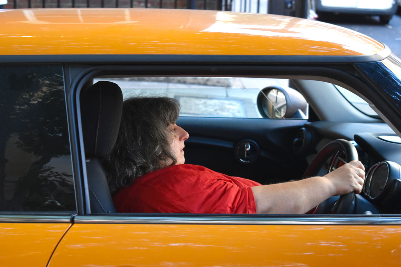 Image of woman reclining in driver's seat of orange car.