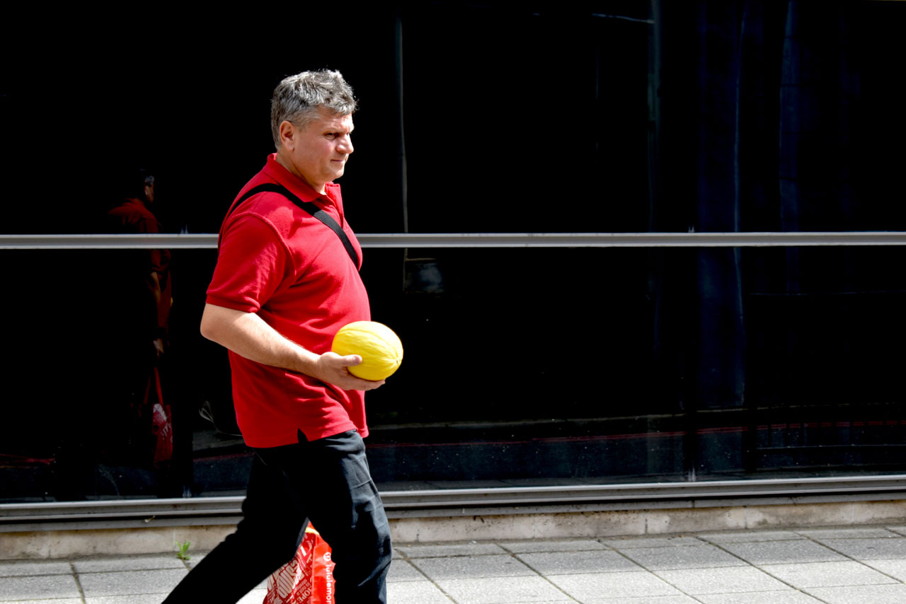 Image of man walking, holding a melon.